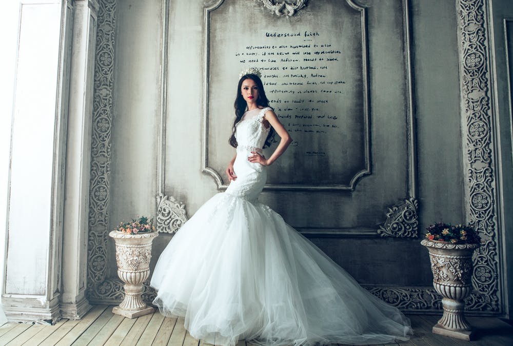 Gorgeous bride in a classical wedding backdrop wear a big, white fully mermaid gown, with long flowing hair.